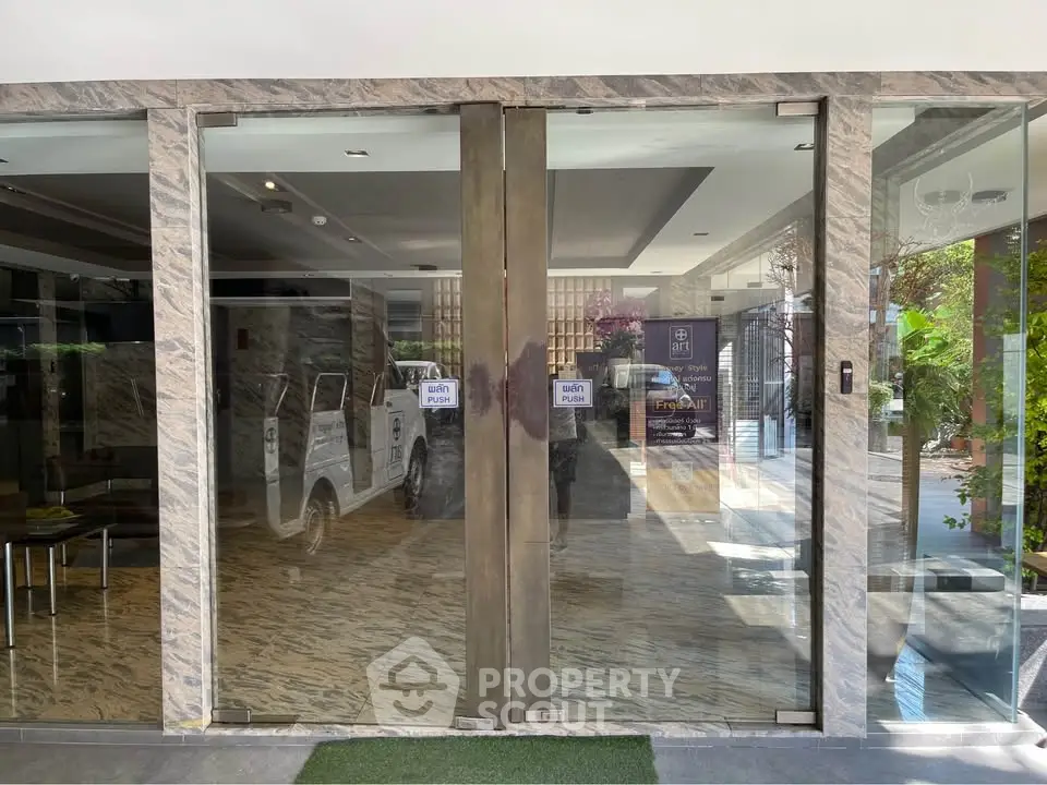 Modern building entrance with glass doors and marble flooring, showcasing luxury and elegance.