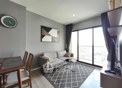Modern living room with stylish decor and large window offering natural light and city view.