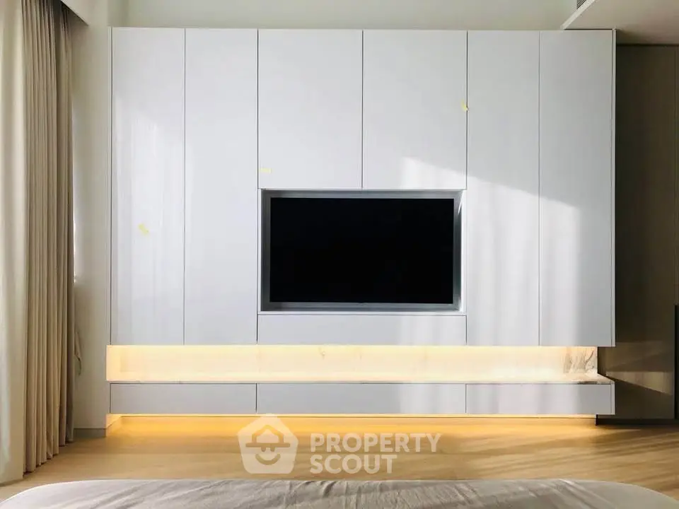 Modern bedroom with sleek built-in TV cabinet and ambient lighting