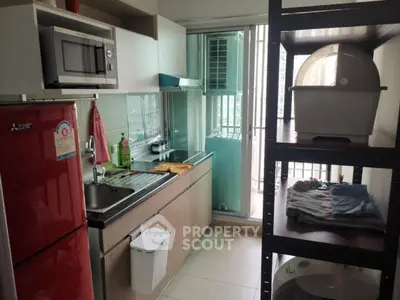Compact kitchen with red fridge, microwave, and balcony access in modern apartment.