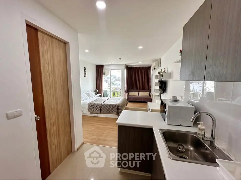 Modern studio apartment with open kitchen and cozy living area, featuring sleek design and natural light.