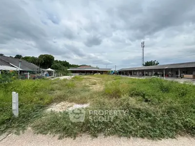 Expansive vacant land plot with potential for development, surrounded by greenery and neighboring structures.