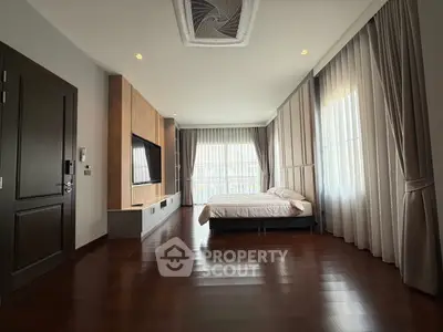 Spacious bedroom with elegant wooden flooring and large windows for natural light.