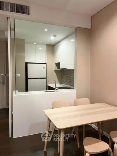 Modern kitchen with open layout and dining area, featuring sleek cabinetry and contemporary design.