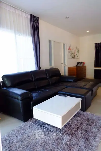Modern living room with black leather sofa and stylish decor