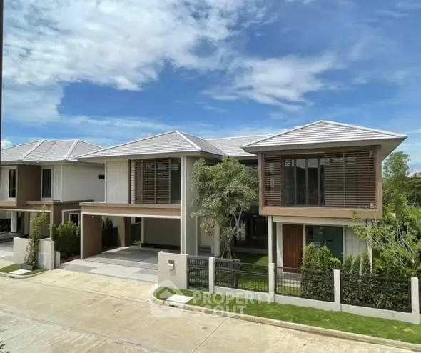 Modern two-story house with sleek design and lush greenery in a suburban neighborhood.