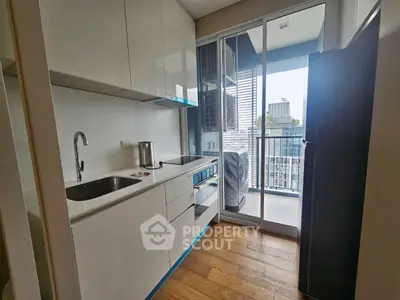 Modern kitchen with sleek cabinetry and balcony view in urban apartment