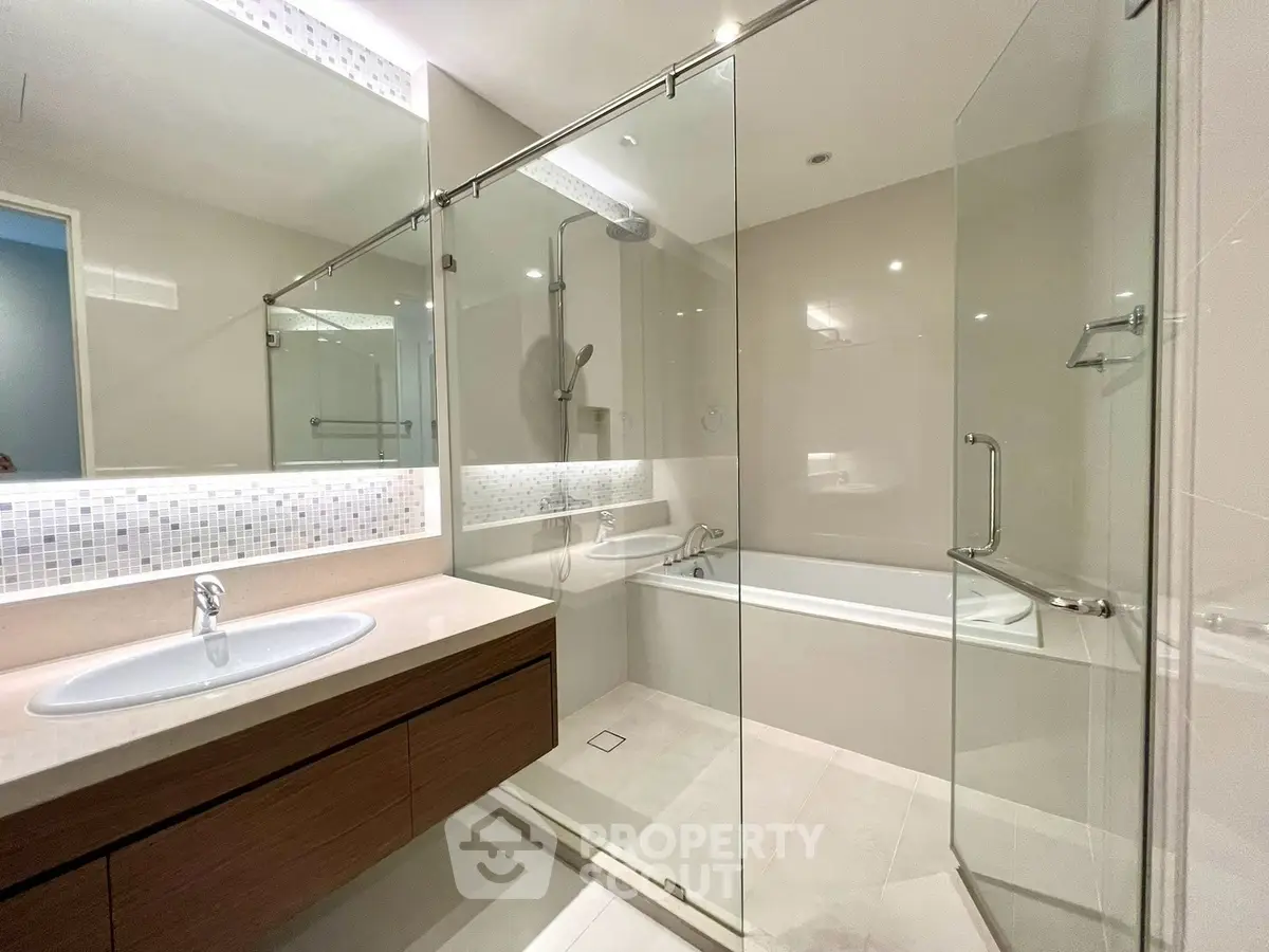 Modern bathroom with glass shower and bathtub, elegant vanity, and sleek design.