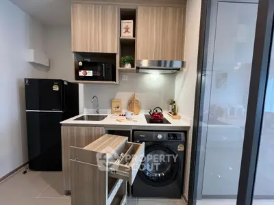 Modern compact kitchen with integrated appliances and washing machine in stylish apartment.