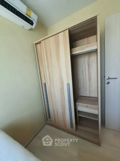 Compact bedroom with wooden wardrobe and air conditioning unit