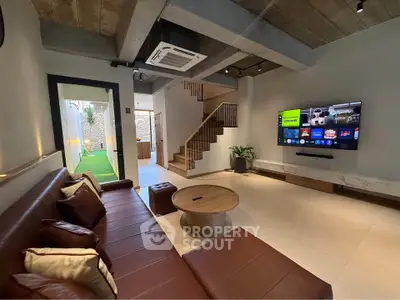 Modern living room with sleek design, leather sofa, and wall-mounted TV, showcasing open layout and stylish decor.