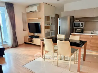 Modern open-layout living room with dining area and kitchen, featuring sleek furniture and natural light.