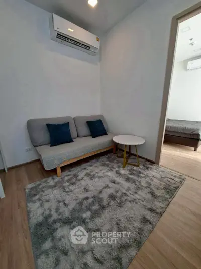 Cozy living room with modern sofa and plush rug, adjacent to a bedroom