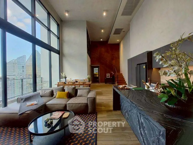 Luxurious modern living room with high ceilings and city view, featuring elegant decor and spacious layout.