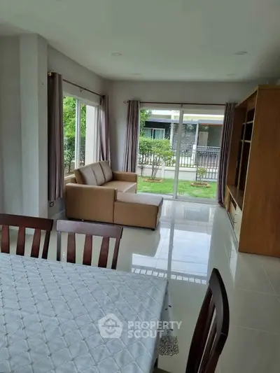 Spacious living room with modern furniture and large windows overlooking a garden.