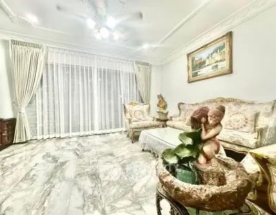 Elegant living room with marble flooring and classic furniture, featuring a decorative sculpture and large window.