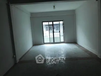 Spacious empty room with large window and balcony access