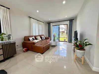 Spacious living room with modern decor and large windows offering natural light and garden view.