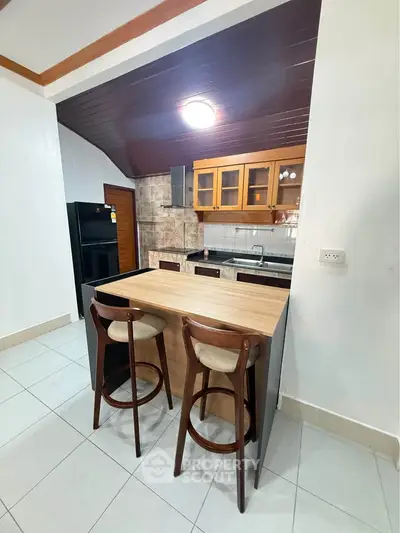 Charming kitchen with open layout and modern appliances, featuring a cozy breakfast bar and stylish wooden cabinetry.