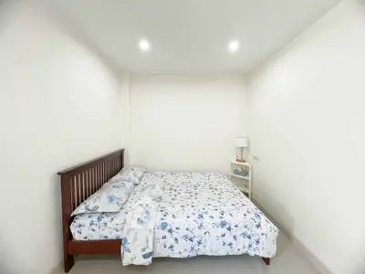 Cozy bedroom with floral bedding and minimalist decor in a bright, inviting space.