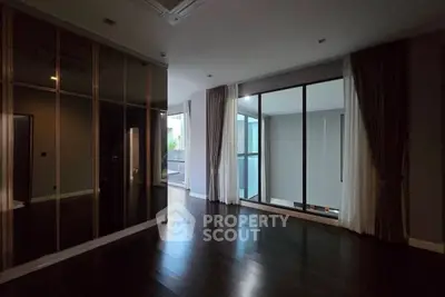 Spacious modern living room with floor-to-ceiling windows and dark wood flooring.