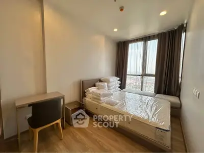 Modern bedroom with large window and wooden flooring in a stylish apartment.