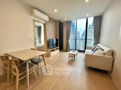 Modern living room with city view, featuring sleek furniture and large windows.