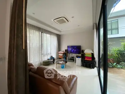 Spacious living room with modern decor and garden view, featuring a cozy leather sofa and entertainment setup.