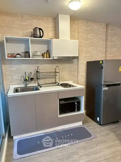 Modern compact kitchen with sleek appliances and stylish cabinetry in a cozy apartment setting.