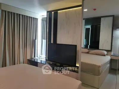 Modern bedroom with sleek design and large mirror reflecting natural light.