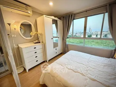 Cozy bedroom with large windows offering a stunning city view, featuring elegant white furniture and soft lighting.