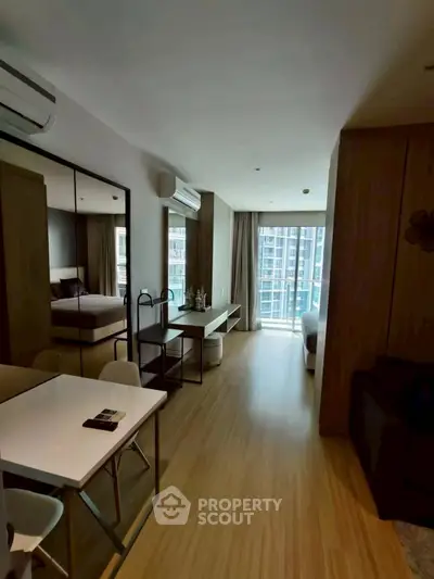 Modern apartment interior with open layout and large windows offering city views.