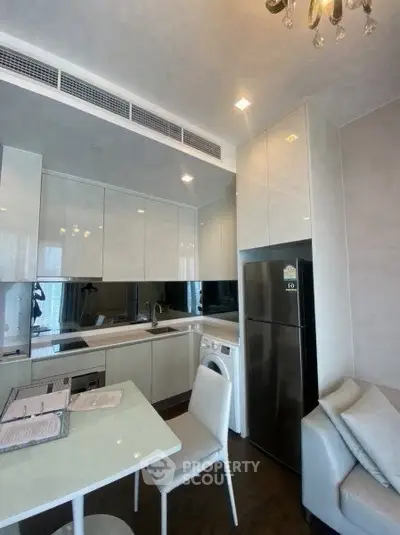 Modern kitchen with sleek cabinetry, integrated appliances, and dining area in a stylish apartment.