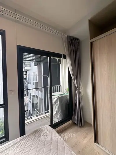 Modern bedroom with balcony access in urban apartment, featuring sleek design and natural light.