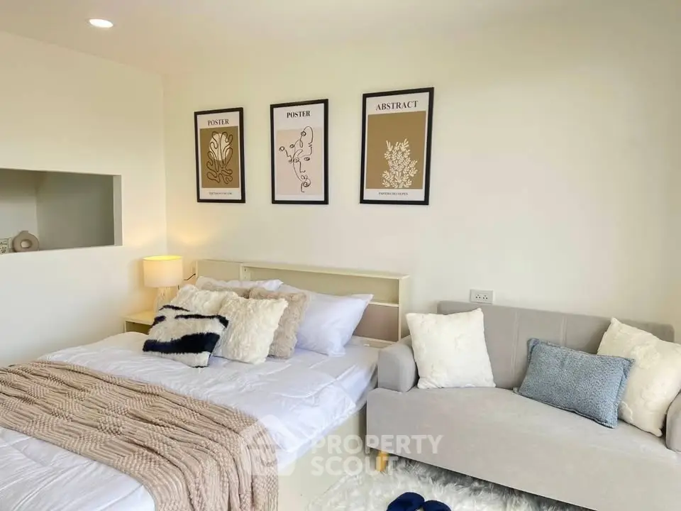 Cozy bedroom with stylish decor, featuring a comfortable bed, modern artwork, and a plush sofa for relaxation.