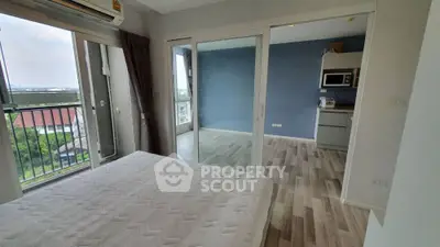 Modern bedroom with balcony and sliding glass doors to kitchen, featuring air conditioning and scenic view.
