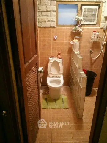Cozy bathroom with tiled walls and floor, featuring a toilet and shower area.