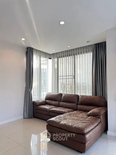 Spacious living room with modern leather sofa and large windows