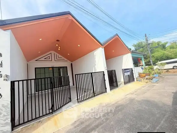 Modern exterior of a stylish house with unique roof design and gated entrance.