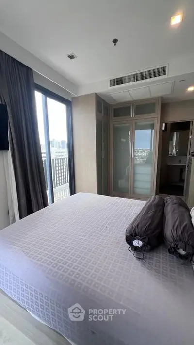 Modern bedroom with large windows and city view, featuring stylish decor and ample natural light.