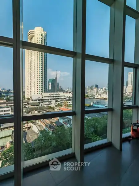 Stunning cityscape view from a high-rise building window, showcasing urban skyline and river.