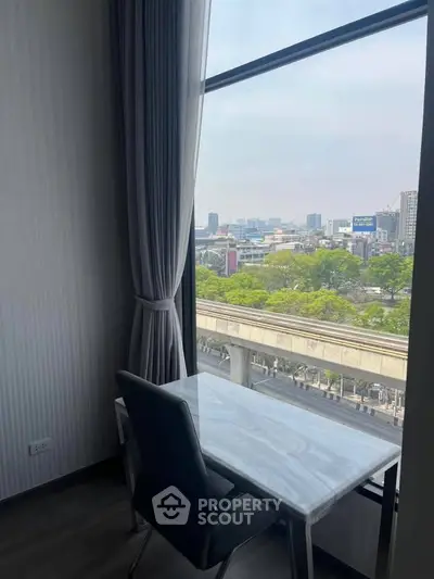 Modern study area with city view from high-rise window, featuring sleek desk and chair.