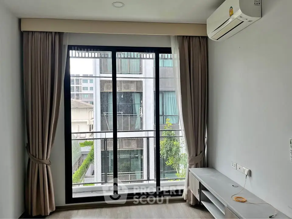 Modern living room with large window and air conditioning, offering a bright and airy atmosphere.