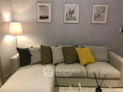 Cozy living room with stylish sofa and decorative pillows, ambient lighting, and modern wall art.