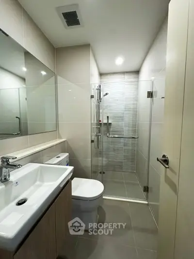 Modern bathroom with sleek design, featuring a glass shower enclosure and contemporary fixtures.
