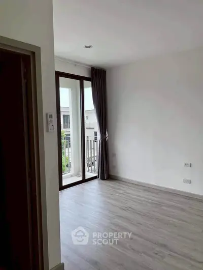 Bright empty room with large window and balcony access, ideal for customization.