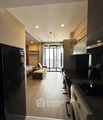 Modern studio apartment with open layout, featuring a compact kitchen and cozy living area leading to a balcony.
