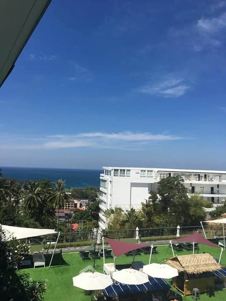 Stunning ocean view from a modern building with lush greenery and outdoor seating area.