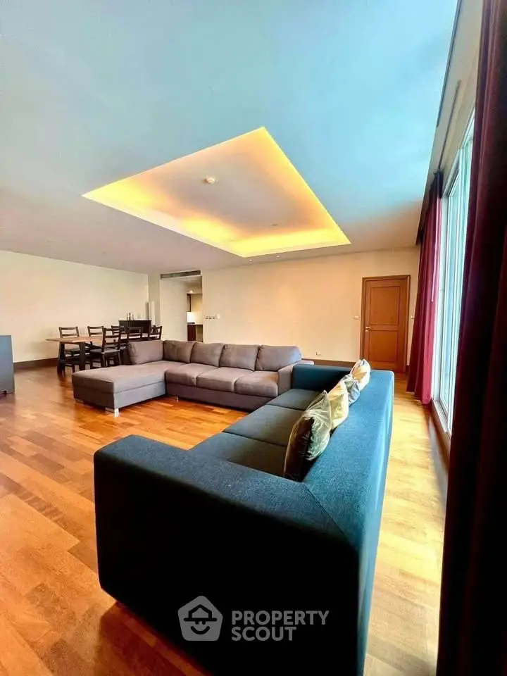 Spacious modern living room with elegant wooden flooring and stylish ceiling lighting.