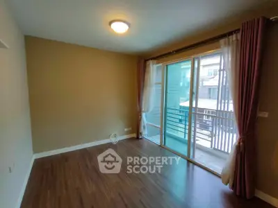 Spacious living room with balcony access and elegant wooden flooring